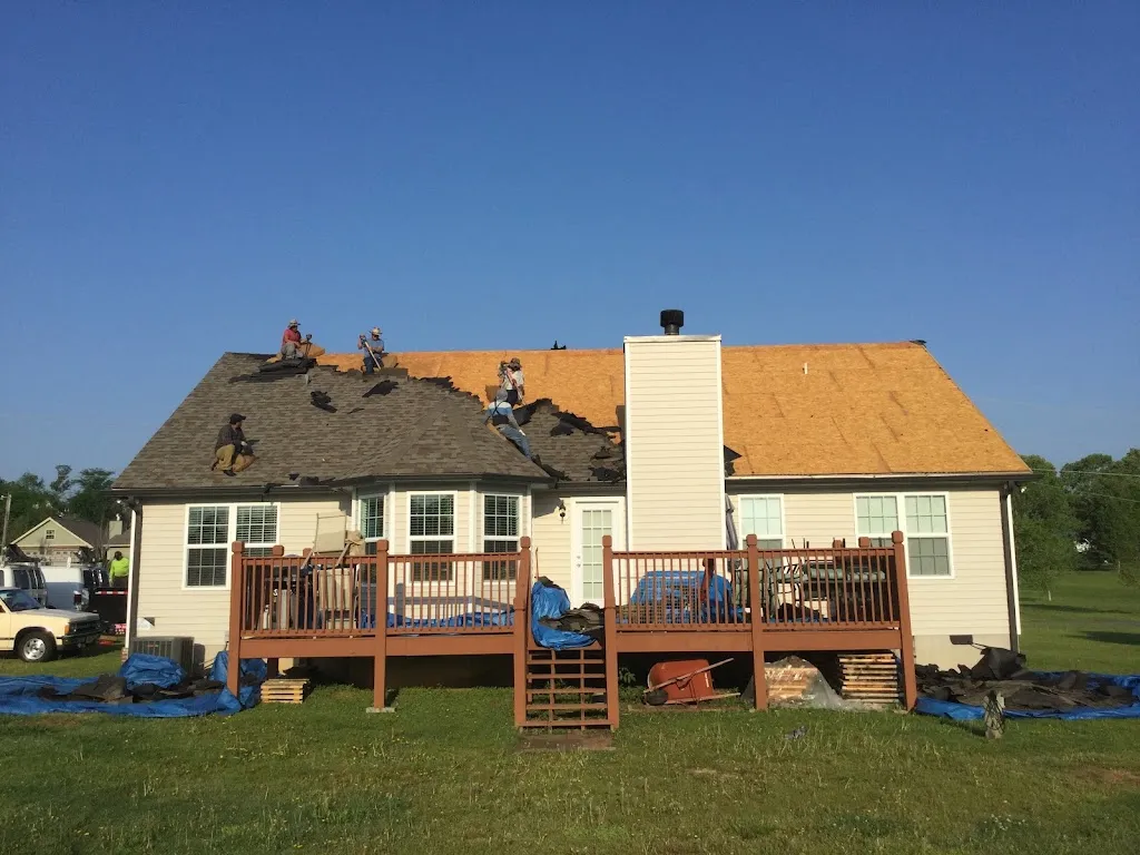 Hill Top crew tearing off a roof with tarps laid around the house